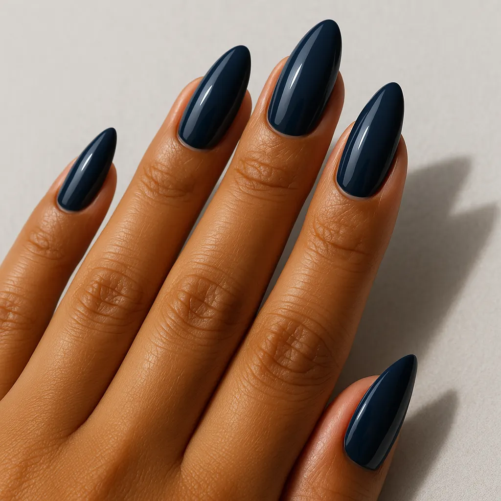Long almond nails in a deep navy blue, on morena skin against a light grey background.