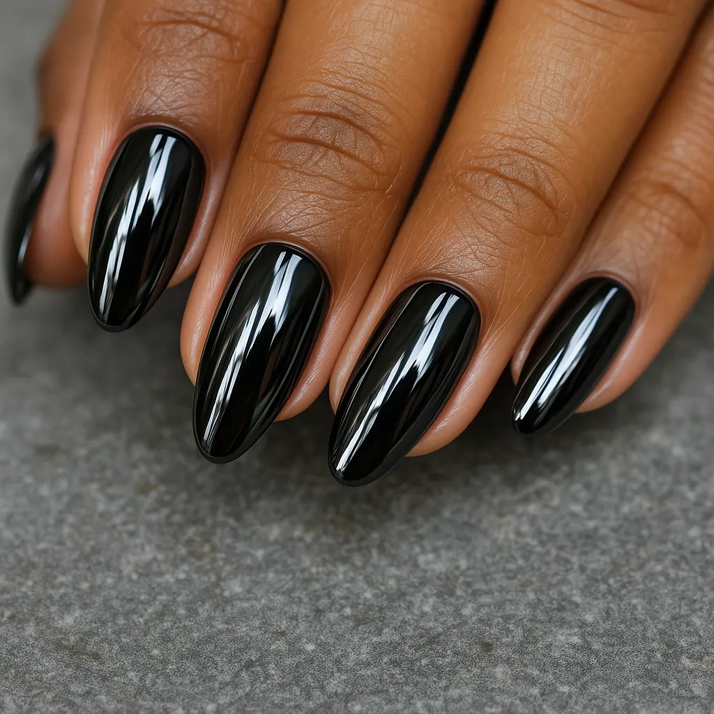 Medium almond nails in glossy black chrome with a mirror shine, on kayumanggi skin on grey stone.