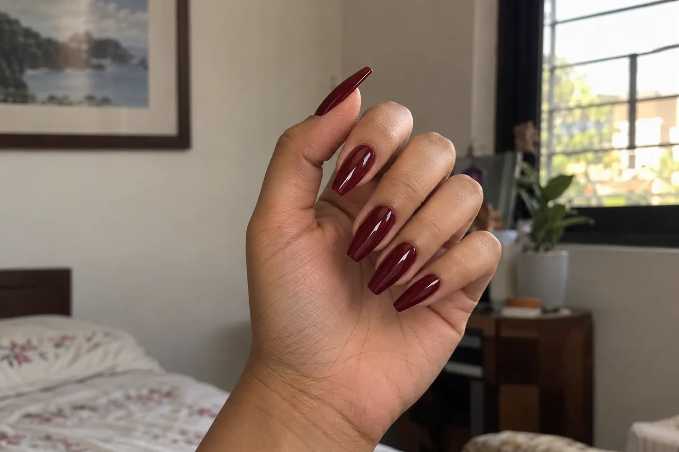 Long coffin extensions in a deep wine red on one hand.