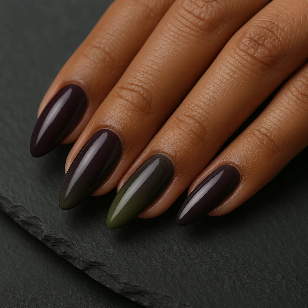 Medium almond nails in deep plum purple shading to moss green, on medium brown skin over black slate.