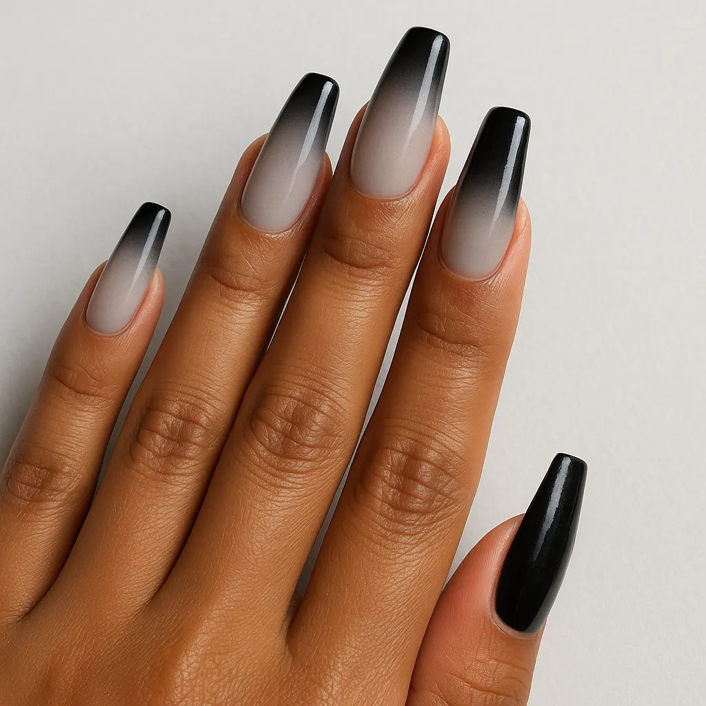 Long coffin nails fading from a pale grey at the cuticle to a dense black at the tip, on morena skin against a light grey background.