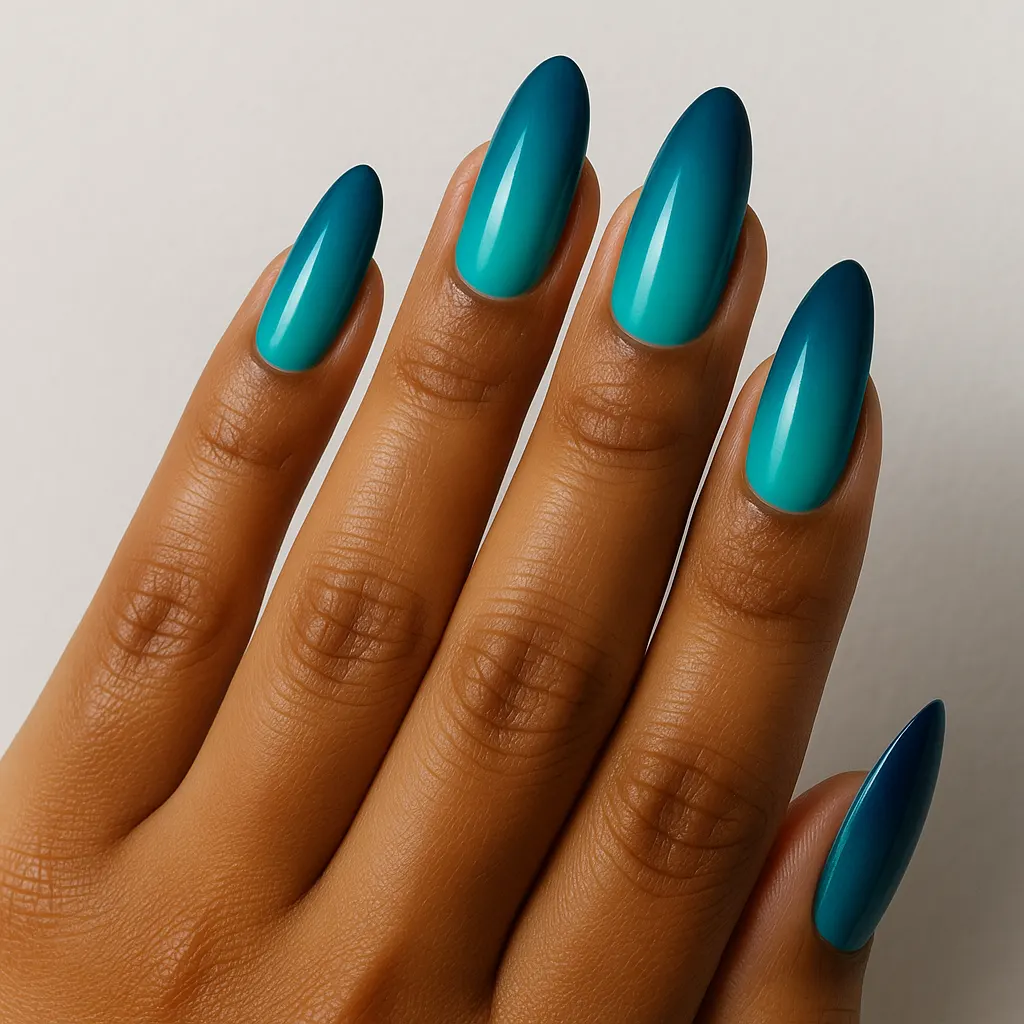 Long almond nails running from teal at the cuticle to a dark navy at the tip, on kayumanggi skin against a light grey background.