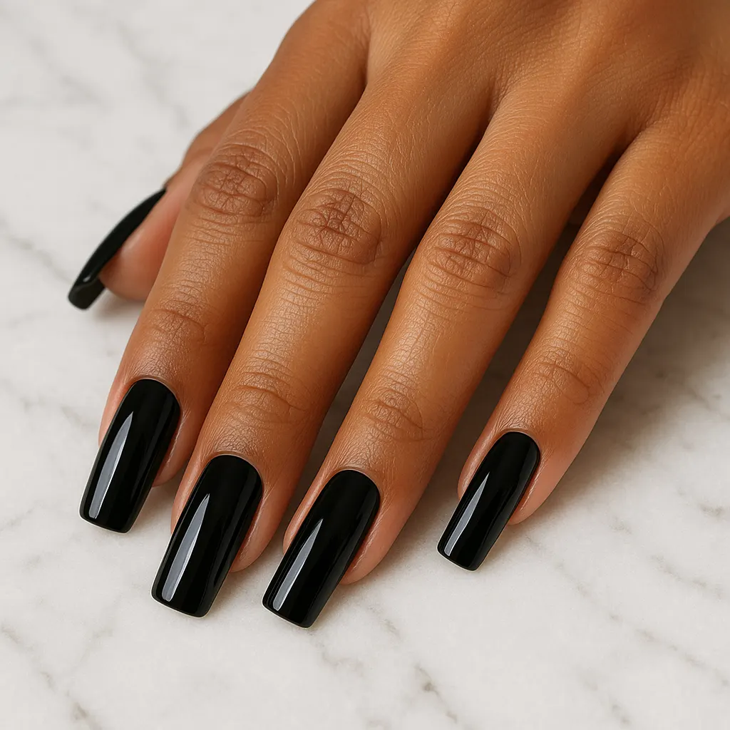Long square nails in glossy jet black on warm tan skin, the hand resting flat on white marble.