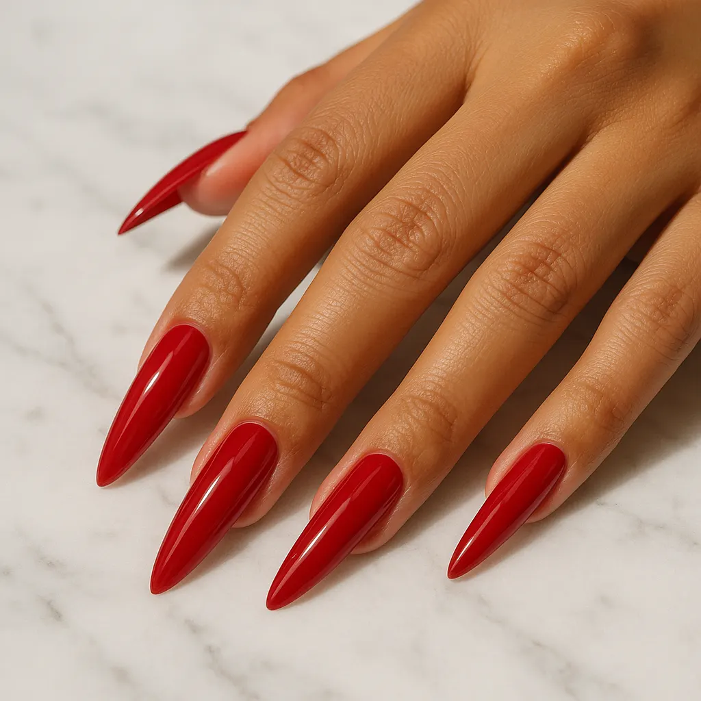 Long stiletto nails in glossy cherry red on light mestiza skin, the hand resting flat on white marble.