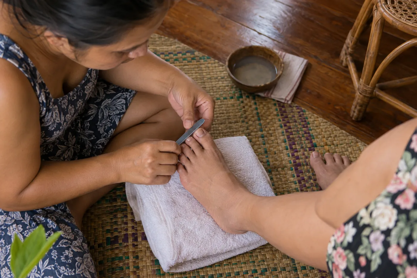 A pedicure in progress on a banig mat at home, seen from above.