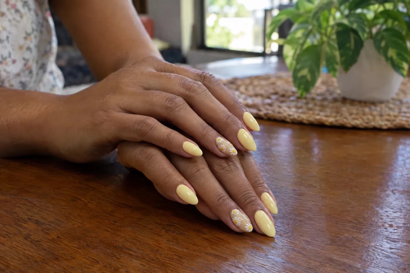 Almond nails in a butter yellow with two accent nails hand-painted with white daisies.